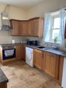 cocina con armarios de madera, fregadero y lavavajillas en Stewarts House, en Newtownstewart