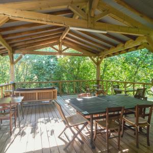 una terraza de madera con mesa verde y sillas en Le Tipi Tropical au bord de la rivière, en Mios