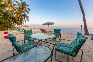 a table and chairs on a beach with the ocean at Beachfront Villa at Islamorada BY THE GLAMHOMES in Islamorada