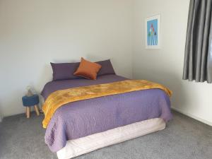 a bedroom with a bed with purple and orange pillows at Kiwiana Gem in Reefton