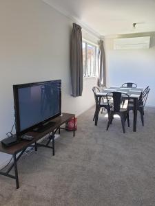 a living room with a television and a table with chairs at Kiwiana Gem in Reefton