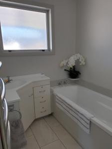 a bathroom with a tub and a sink and a window at Kiwiana Gem in Reefton