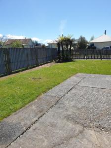 a yard with a fence and a grass field at Kiwiana Gem in Reefton