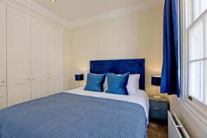 um quarto com uma cama azul com almofadas azuis em Hyde Park Paddington spacious London Home em Londres