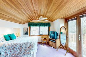 um quarto com uma cama, uma ventoinha de tecto e uma televisão em Cannon Beach Cottage em Cannon Beach