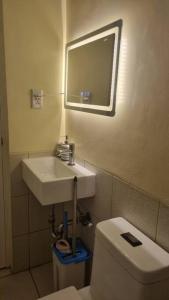 a bathroom with a sink and a toilet and a mirror at CityLofts Plainview in Mandaluyong corner unit in Manila