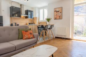 a living room with a couch and a table at Appartement T3 63m2 - L'Atypique et son Jardin de 350m2 au cœur de Digne in Digne-les-Bains