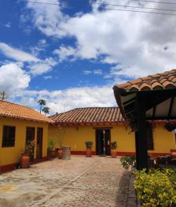 um edifício amarelo com um telhado de azulejo e um pátio em Casa Finca El Mirador frente a la laguna de Fúquene em Fúquene