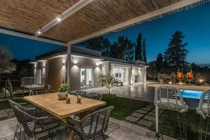a patio with a table and chairs and a pool at Melissia Luxury Villa in Zakynthos Town
