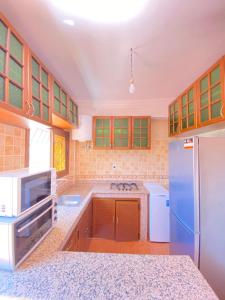 una cucina con armadi in legno e frigorifero blu di CENTRE D'ESTIVAGE IMi OUADDAR a Agadir nʼ Aït Sa