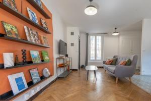 een woonkamer met een bank en een oranje muur bij Appartement T3 63m2 - L'Atypique et son Jardin de 350m2 au cœur de Digne in Digne-les-Bains