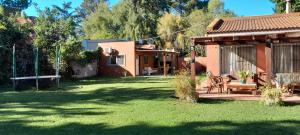 einen Hinterhof mit einem Haus und einem Garten mit grünem Gras in der Unterkunft La Adelita in Chascomús
