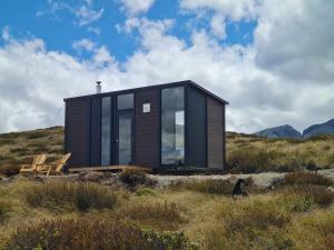 a black tiny house on a hill with a bench at Lake Stella 2 - Rock Wren in Mt Lyford