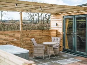 a patio with a table and chairs and a fence at Swallow Lodge - Uk42540 in Winforton