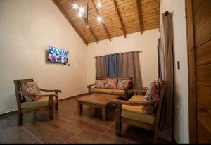 ein Wohnzimmer mit Stühlen, einem Tisch und einem TV in der Unterkunft VillaLunaCaridad in Jarabacoa