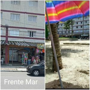 a rainbow umbrella in the sand next to a building at Lindo apartamento em frente a praia in Praia Grande