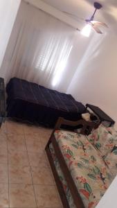 a room with two beds and a ceiling fan at Lindo apartamento em frente a praia in Praia Grande