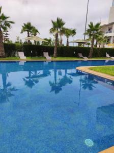 a large swimming pool with blue water and palm trees at HEAVEN BEACH in Sidi Rahal