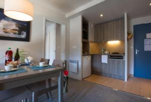 eine Küche und ein Wohnzimmer mit einer Theke und einem Tisch in der Unterkunft Résidence Pierre & Vacances L'Archipel in Perros-Guirec