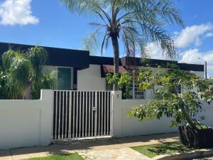 uma cerca branca em frente a uma casa com uma palmeira em CasaMar House Whit Pool 3 Bedrooms 3 Bathrooms em San Juan
