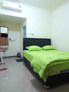 a bedroom with a bed with green sheets and a sink at AG HOME STAY in Labuan Bajo