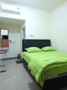 um quarto com uma cama com lençóis verdes e um lavatório em AG HOME STAY em Labuan Bajo