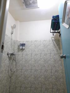 a shower in a bathroom with a tiled floor at AG HOME STAY in Labuan Bajo