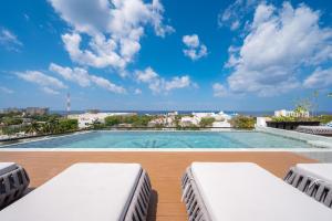 a swimming pool with two chaise lounges at Kippal - Modern Oasis - ApartHotel in Cozumel