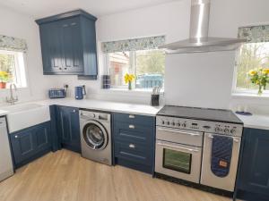 a kitchen with blue cabinets and a washing machine at Orchard House in Leominster