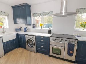 Una cocina con armarios azules y lavadora. en Orchard House, en Leominster