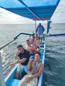 a group of men sitting on a boat in the water at Family Hostel in Lovina