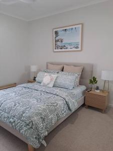 um quarto com uma cama com um edredão azul em Unwind in Woombye em Woombye