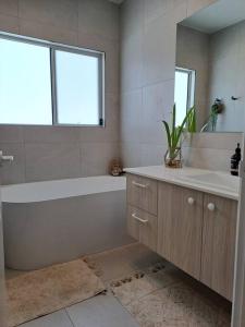 La salle de bains est pourvue d'une baignoire, d'un lavabo et d'un miroir. dans l'établissement Unwind in Woombye, à Woombye