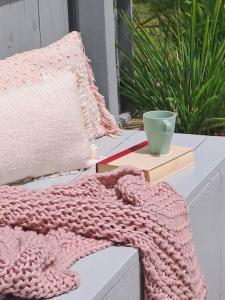 a pink crochet blanket sitting on a bench with a bowl at Unwind in Woombye in Woombye