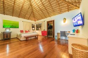 a living room with a bed and a tv and a table at Vilarejo Barra Grande in Barra Grande