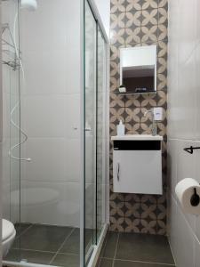 uma casa de banho com um chuveiro, um lavatório e um espelho. em ReCanto dos Passáros - Guaratiba em Pedra de Guaratiba