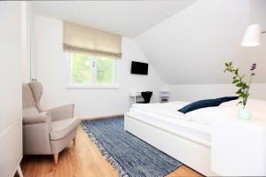 a white bedroom with a bed and a chair at FeWo Bark Middenmang in Wustrow