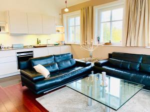 a living room with black leather furniture and a glass table at Strandquartier 31 "Quartier 1" in Wustrow