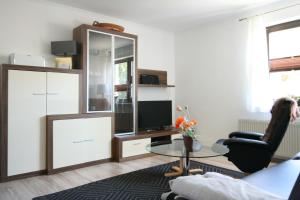 ein Wohnzimmer mit einem TV und einem Glastisch in der Unterkunft Strandläufer in Wustrow