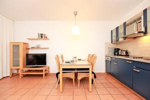 a kitchen with a table and chairs and a television at Dünenwald WE 14 in Neuhaus