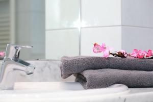 La salle de bains est pourvue d'un lavabo, de serviettes et de fleurs roses. dans l'établissement Haus Kranich App 426, à Neuhaus
