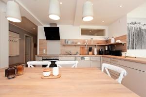 una grande cucina con un tavolo di legno e sedie bianche di Kleine Robbe Whg1 a Wustrow Altre 31 foto