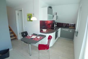 a kitchen with a table and a red chair at Haus Dünenrot OG-Whg DR-04 in Neuhaus