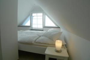 a bedroom with a bed with a window and a candle at Haus Dünenrot OG-Whg DR-04 in Neuhaus