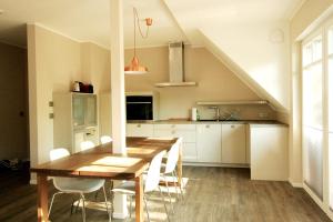 NeuhausにあるHaus Strandkieker Whg 4のキッチン(木製テーブル、白いキャビネット付)