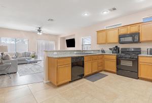 a kitchen with wooden cabinets and a living room at Beautiful Spacious Single Story Vegas Home in Las Vegas