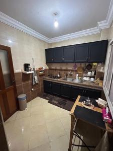 a kitchen with black cabinets and a sink and a table at chambre privée in Kenitra