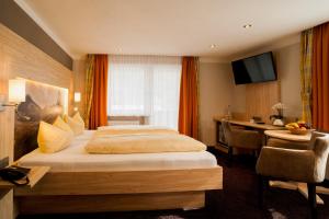 シェーナウ・アム・ケーニッヒスゼーにあるHotel Brunneckのベッドとデスクが備わるホテルルームです。