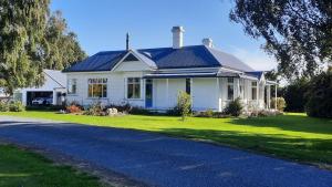 a white house with a blue roof and a driveway at Greenfield Country Homestay in Pukeawa