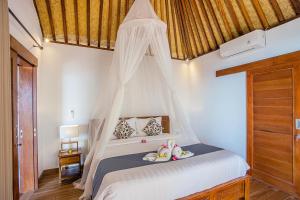 a bedroom with a white bed with a canopy at Nusa Veranda Sunset Villas & Restaurant in Nusa Lembongan